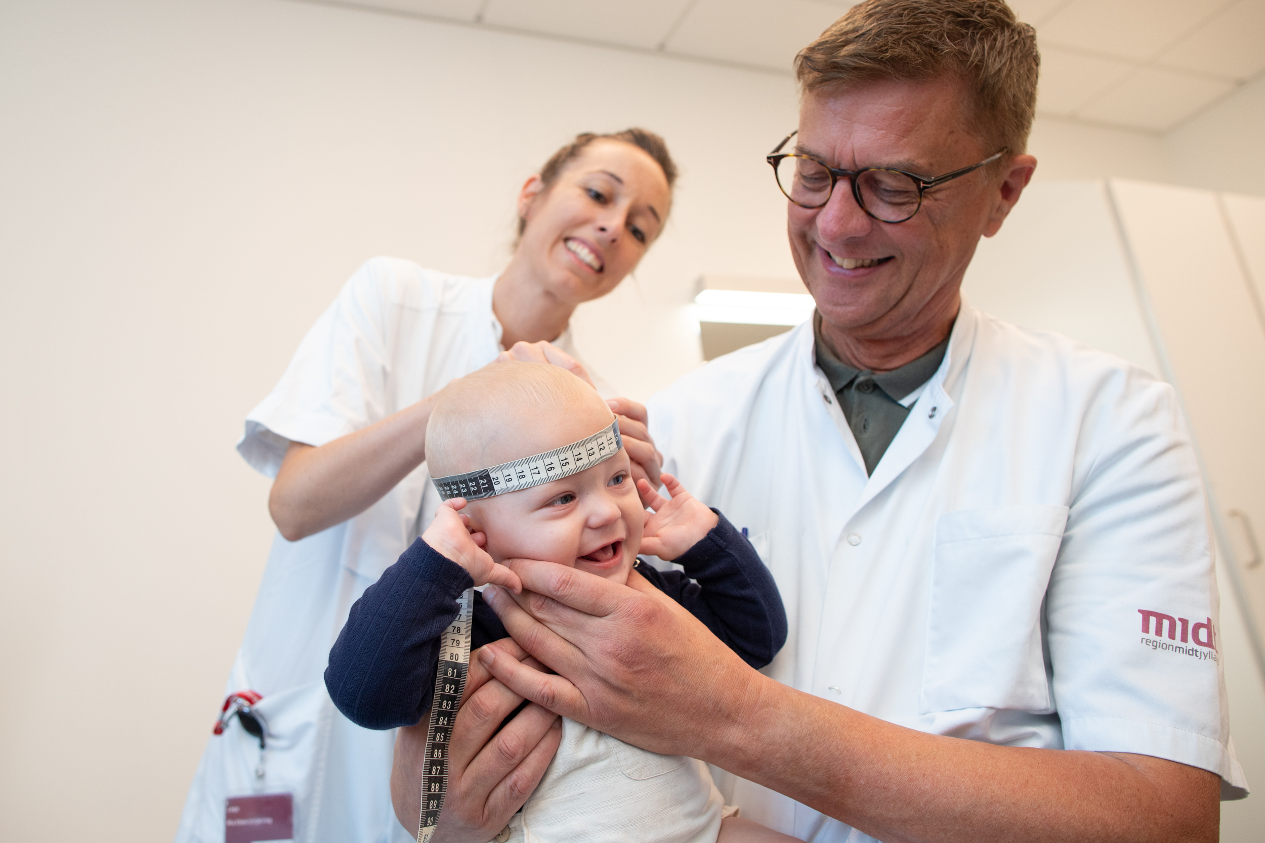 Billede af læge, der måler hovedet på en baby med et målebånd